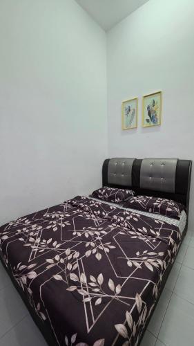 a bed with a brown and white blanket on it at Andalus Homestay in Jerantut