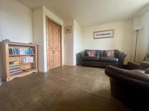 a living room with a couch and a book shelf at The Holmes Barn - Sleeps 16 - Pet friendly in Buxton