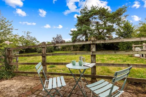 a table and chairs in front of a fence at Mulberry Cottage in Nettlebed