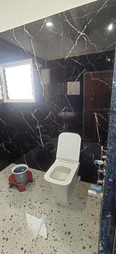 a bathroom with a toilet and a black wall at statue of unity villa in Garudeshwar