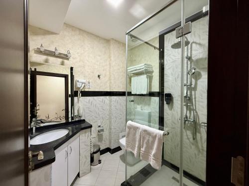 un bagno con doccia in vetro e lavandino di Wellmore Resort a Yusufkhona