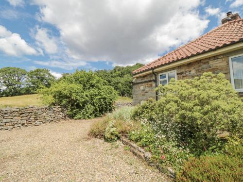 a stone house with a stone wall and a yard at Low Muffles Bridge in Pickering