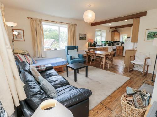 a living room with a leather couch and a kitchen at Low Muffles Bridge in Pickering