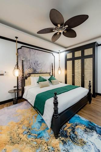 a bedroom with a large bed with a ceiling fan at Cozy An Luangprabang Hotel in Luang Prabang