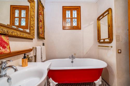 a bathroom with a red bath tub next to a sink at Riad Asrari in Marrakech