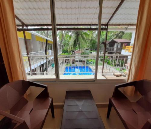 a room with two chairs and a window with a view of a pool at Beach Walk Resort-100 meters to Morjim Beach in Morjim