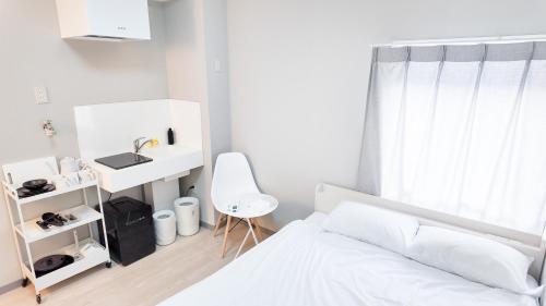 a white bedroom with a bed and a desk at 9stay蔵前 in Tokyo