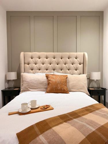 a large bed with two cups and a tray on it at Cosy 2 Bed Retreat with FREE Secure Parking in Nottingham