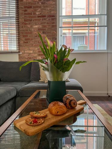 a table with a tray of bread and a vase of flowers at Cosy 2 Bed Retreat with FREE Secure Parking in Nottingham