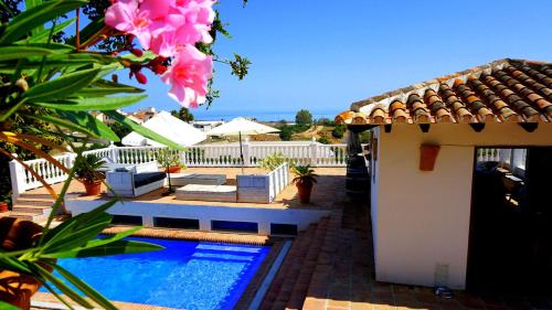 a swimming pool next to a house with a pink flower at Caravan in Finca Molino in Almayate with with pool, family touch and dog madness in Almayate Alto