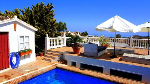 a house with a swimming pool and an umbrella at Caravan in Finca Molino in Almayate with with pool, family touch and dog madness in Almayate Alto