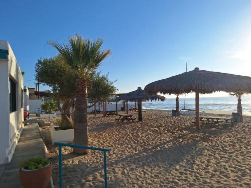 a beach with umbrellas and benches and the ocean at #36 Bungalow Seaside Hotel & Victors RV Park in San Felipe