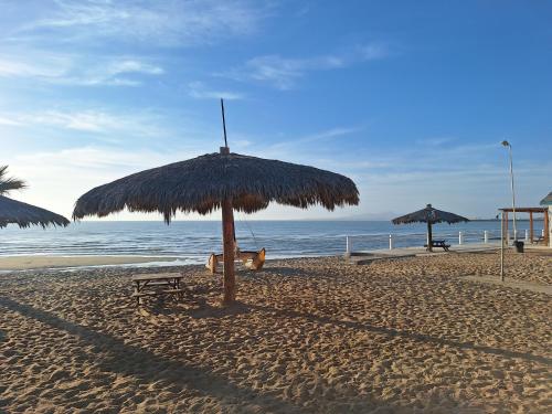 a straw umbrella on a beach with the ocean at #36 Bungalow Seaside Hotel & Victors RV Park in San Felipe