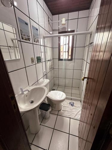 a white bathroom with a sink and a toilet at Pousada Sanhaço in Abraão