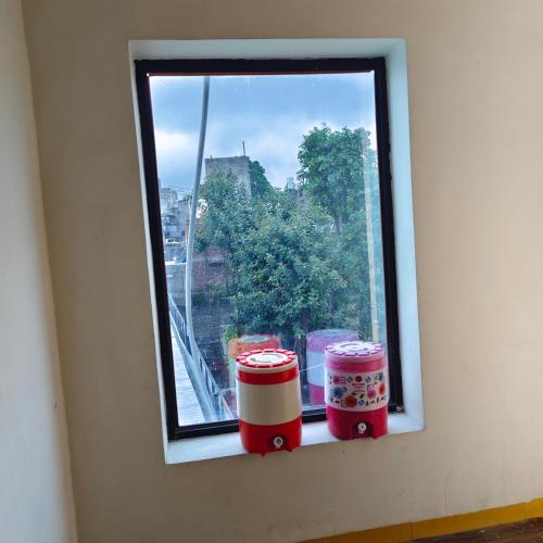 a window with three jars sitting on a window sill at Dev Kripa Geust House in Ujjain