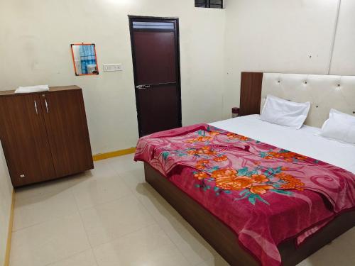 a bedroom with a large bed with a red blanket at Dev Kripa Geust House in Ujjain