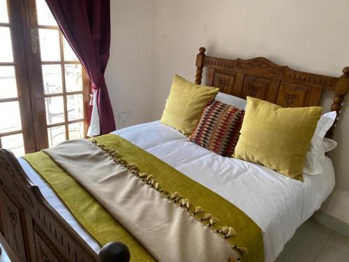 a bed with white sheets and yellow pillows at La Mia casa in Gaborone