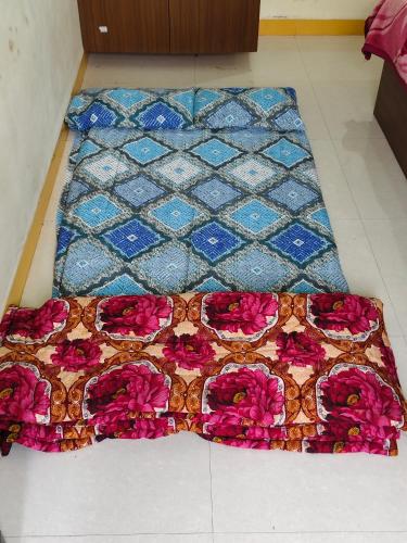 a quilt on the floor with pink flowers on it at Dev Kripa Geust House in Ujjain