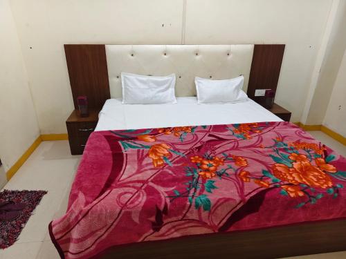 a large bed with a colorful blanket on it at Dev Kripa Geust House in Ujjain