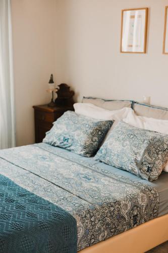 a bed with blue and white sheets and pillows at Dinora Villa in Agios Ioannis Tinos