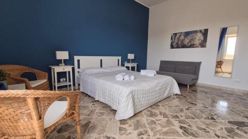 a bedroom with a bed and a chair and a couch at Angolo del Mare - Case Libeccio e Blu Marino in Favignana