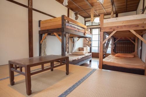 a room with two bunk beds and a table at 伊勢ゲストハウス紬舎-Ise Guesthouse Tsumugiya- in Ise