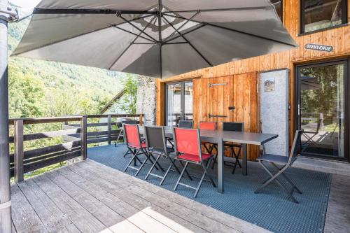 une table et des chaises avec un parasol sur une terrasse dans l'établissement Breizh Chalet - 14 personnes, à Saint-Colomban-des-Villards
