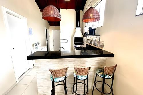 una cocina con encimera negra y taburetes en 01 - Apto Pé na Areia - Sacada na Praia, en Palhoça