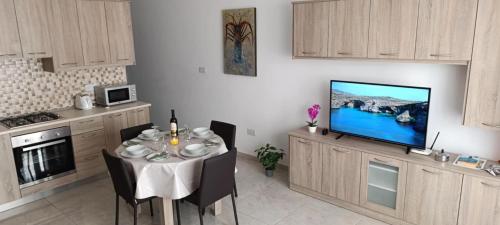 a dining room with a table and a television in a kitchen at Side Sea View D, Steps Away to Bugibba Jetty, For the Blue Lagoon Boats and Other Islands in St Paul's Bay