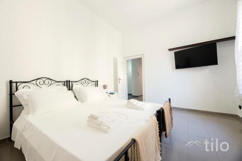a bedroom with a white bed with a tv on the wall at Airport 8 Minutes, 2BR, Terrace, By Tilo in Genova