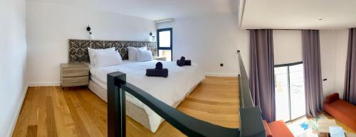 a bedroom with a large bed with white sheets and wood floors at Villa Octagon Essaouira in Essaouira