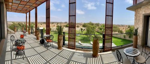 a porch with chairs and tables and a view of a field at Villa Octagon Essaouira in Essaouira