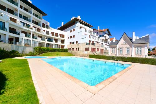 a swimming pool in front of a large building at Ocean - Duplex apartment 65m from the beach with pool and parking in São Martinho do Porto