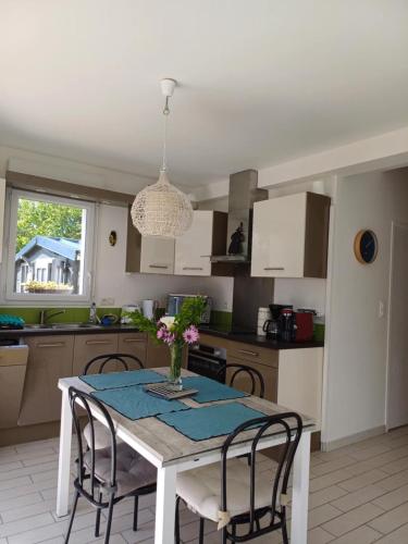 une cuisine avec une table, des chaises et un vase de fleurs dans l'établissement Maison tout confort au calme à 300m de la mer et du GR34 avec jardin, à Loctudy