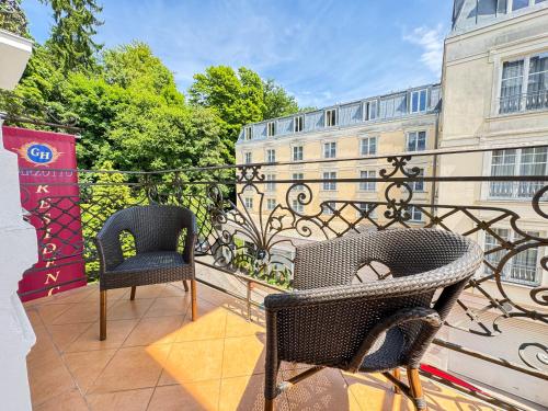 a balcony with two chairs and a building at Residence Romanza in Mariánské Lázně
