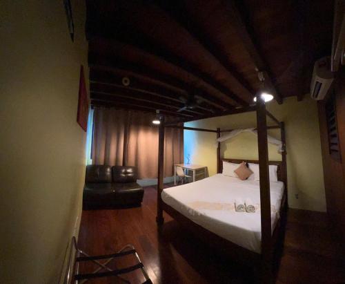 a bedroom with a canopy bed and a couch at Hotel Lang Hoose in George Town