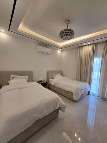 a bedroom with two beds and a chandelier at Luxury Furnished Apartment in Salalah Center in Salalah