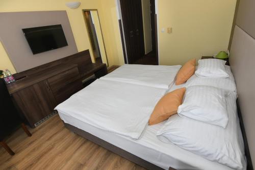 a bed with white sheets and pillows in a bedroom at Jade Hotel-Ezüsthíd Hotel in Veszprém