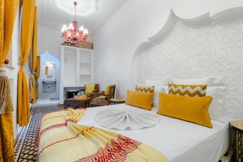 a bedroom with a white bed with yellow pillows at Riad Asrari in Marrakech