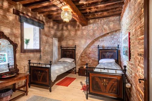 Gioiellaにある16th Century Townhouse, Large Garden Near Lake, Tuscany and Umbria - Sleeps 18のレンガの壁にベッド2台が備わるベッドルーム1室