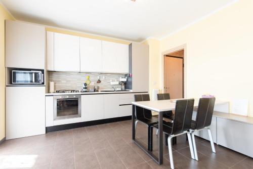a kitchen with white cabinets and a table and chairs at Fra Cielo e Mare - Private parking & Wi-Fi in Castellaro