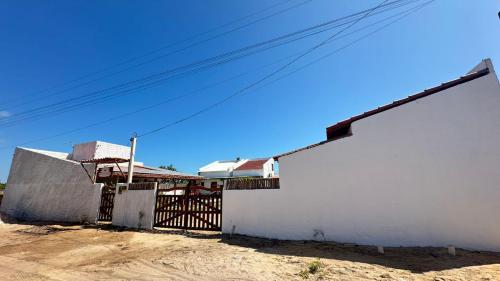 a white building with a gate and a fence at Suite Cajueiro in Barrinha