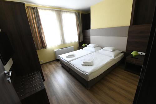 a bedroom with a bed with white sheets and pillows at Jade Hotel-Ezüsthíd Hotel in Veszprém