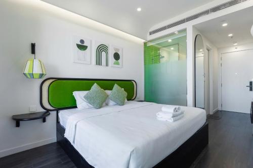 a bedroom with a large white bed with a green headboard at Capella Apartment Fireworks and Ocean View- Hillside Phu Quoc in Phu Quoc