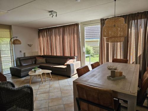un salon avec un canapé et une table dans l'établissement Prachtige vakantiewoning-6P-afgesloten tuin-2 fietsen-dichtbij het strand, à Julianadorp