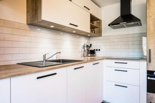 a kitchen with white cabinets and a sink at Charmant Duplex Au Pied Des Pistes in Albiez-Montrond