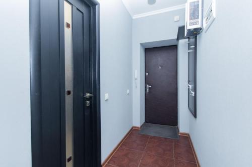 a hallway with a black door and a brown floor at Seven Apartments 66 in Vyshneve