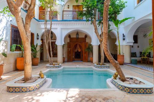 a courtyard with a pool with trees in front of a building at Riad Asrari in Marrakech