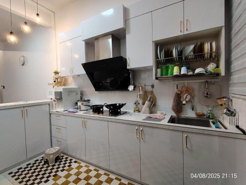 a kitchen with white cabinets and a black and white checkered floor at Teratak Asyakira in Bedung