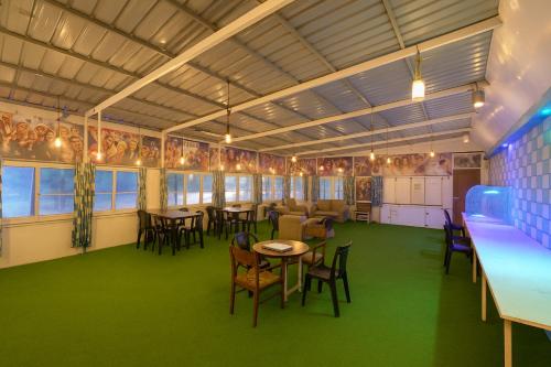 a dining room with tables and chairs and green carpet at Taj City Hotel in Agra